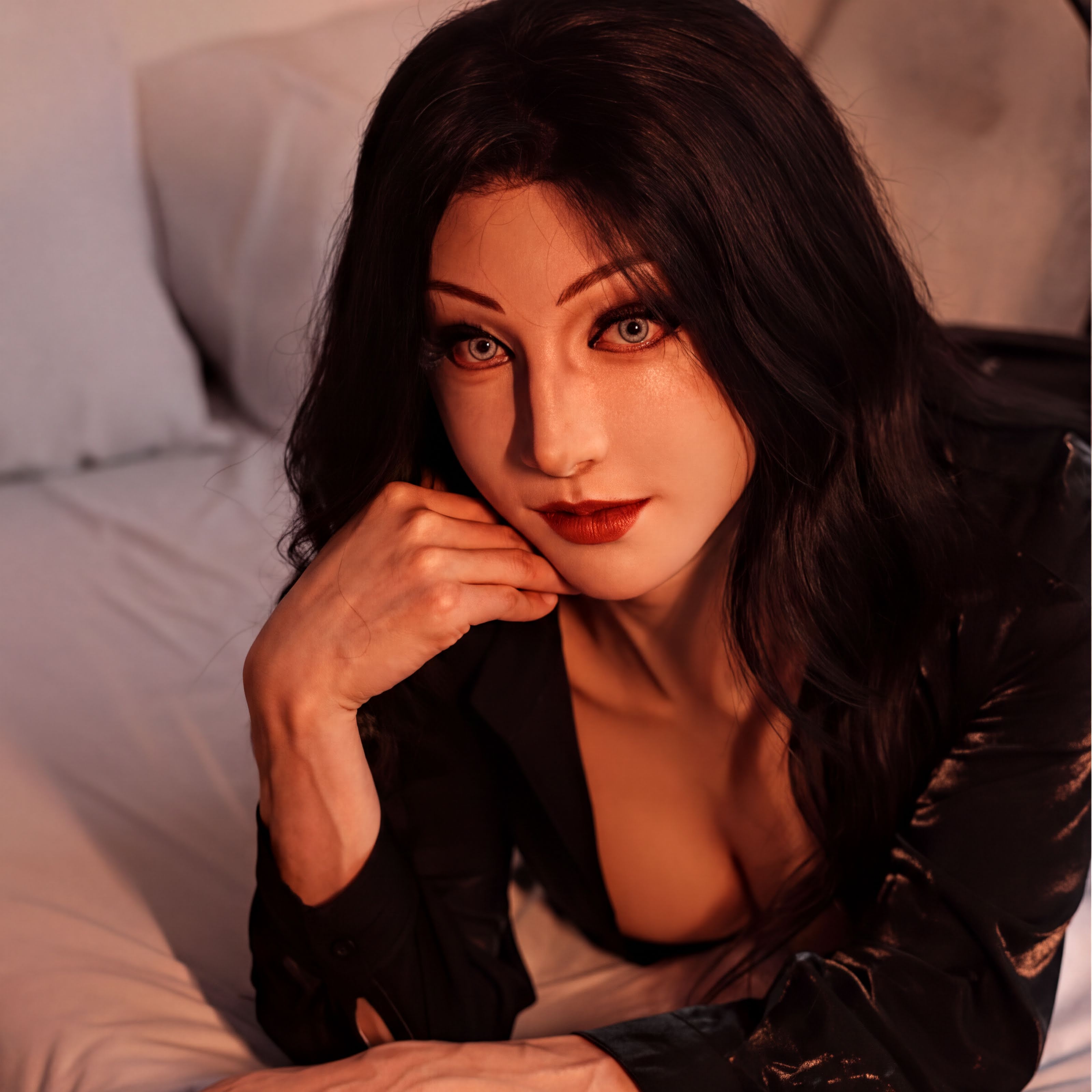 A woman with long dark hair and striking red lips is the central focus of the image, resting her chin on her hand in a thoughtful pose.