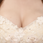 A close-up view of a woman's bust, featuring a delicate white lace dress adorned with intricate floral patterns.